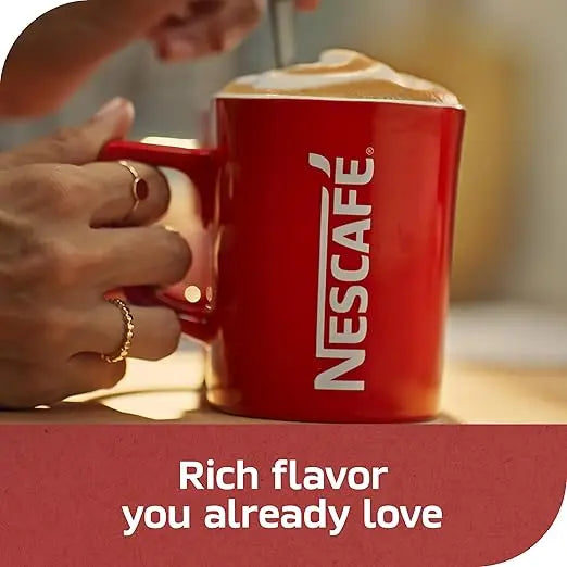 Red Nescafe mug with a hand holding it, on a blurred background
