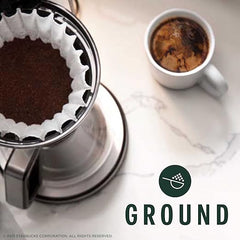 Coffee filter with ground coffee and a brewed cup on a marble surface, featuring the Starbucks 'Ground' logo.