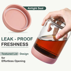 Glass container with pink textured lid holding a drink, labeled 'Airtight Seal' and 'Leak-Proof Freshness'.